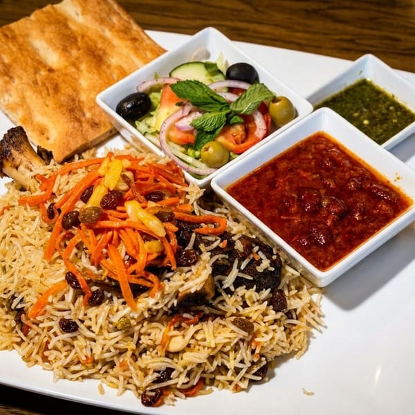 Afghan lamb shank pilaf with rice, carrots, raisins, flatbread, salad, and two dipping sauces.